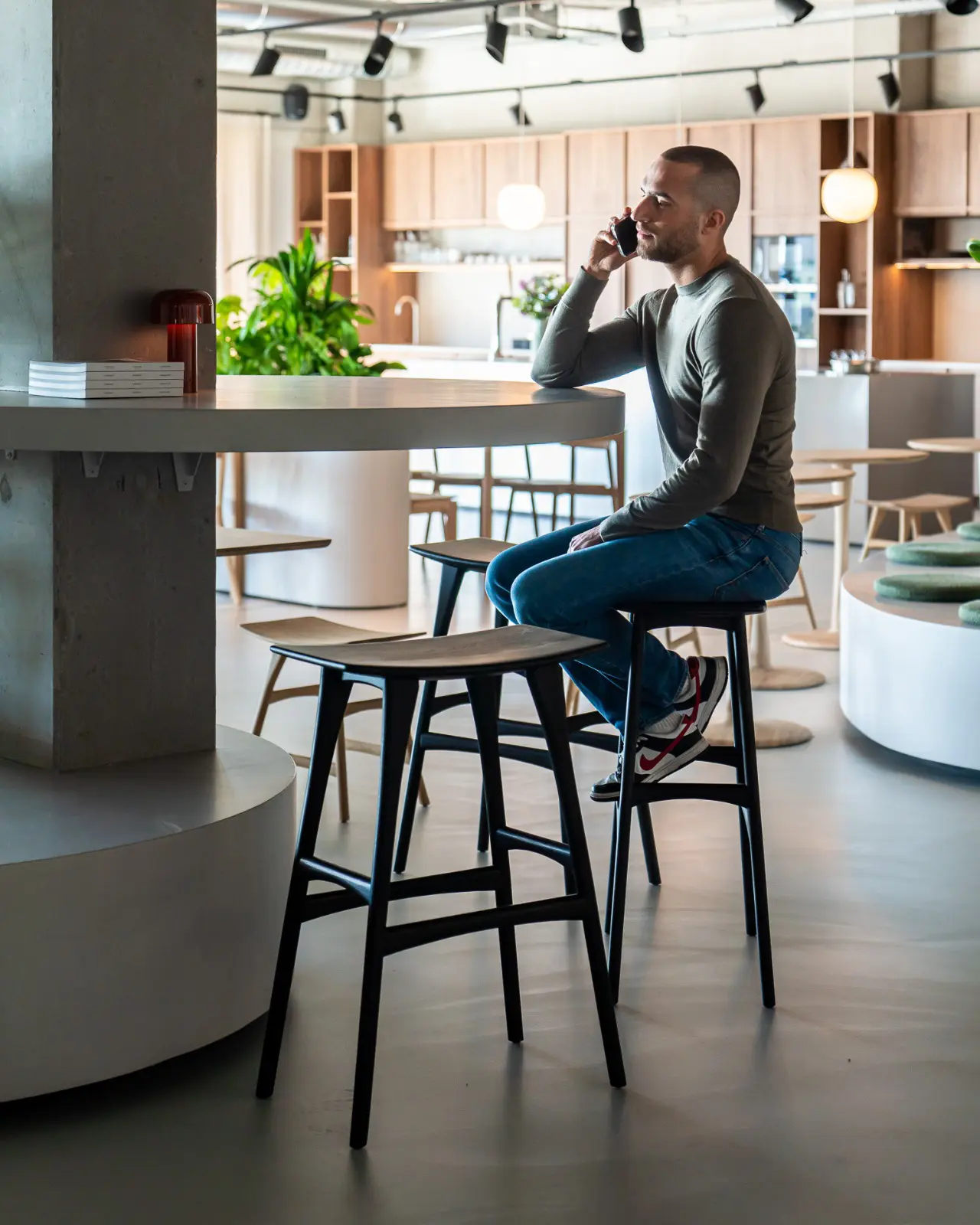 goode studio lifestyle man sitting on barstool while talking on phone